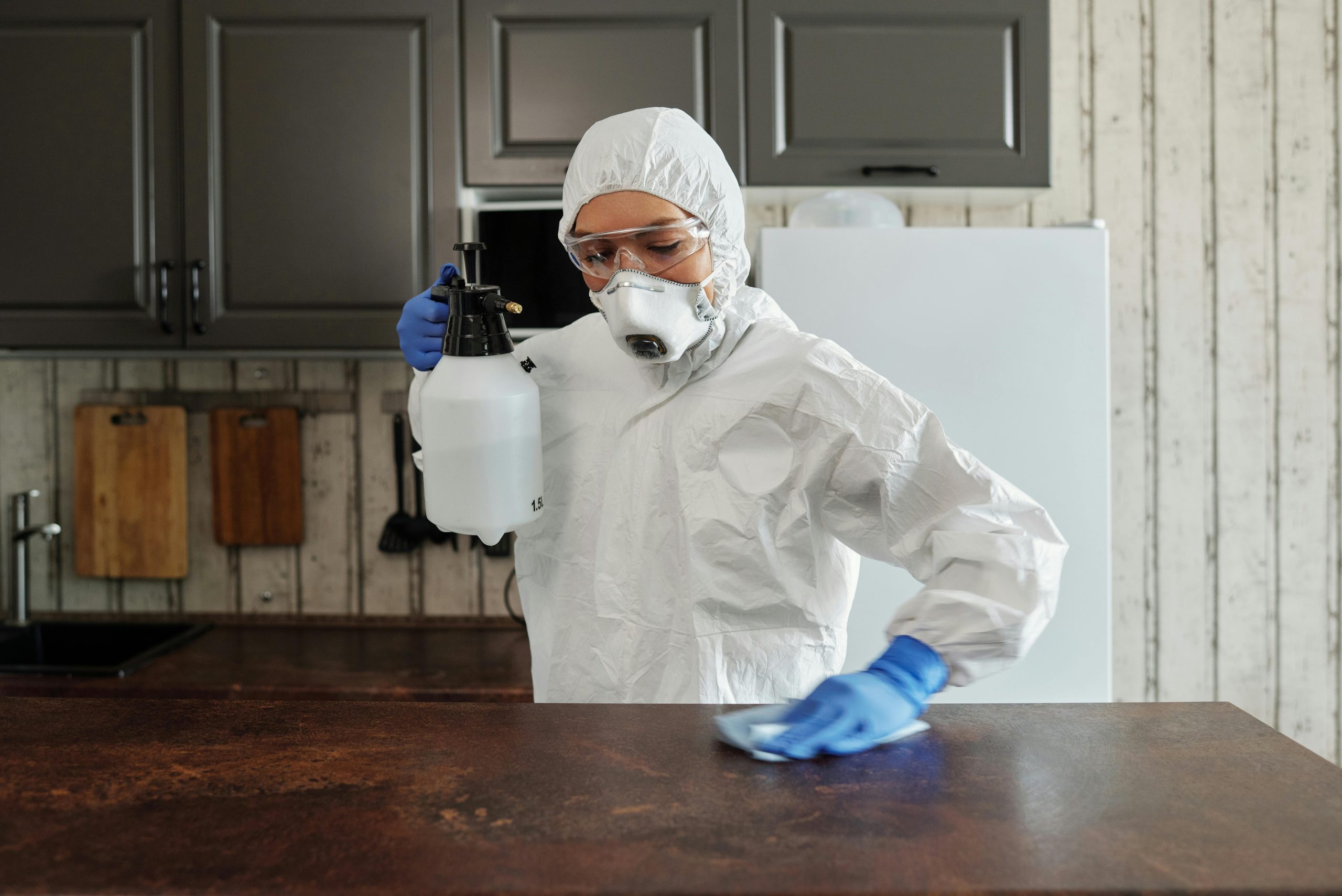 Woman wearing safety equipment, cleaning the kitchen table